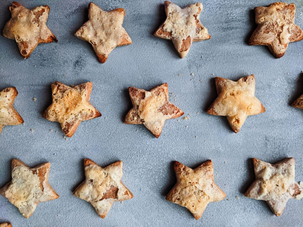 Vue de dessus de délicieux biscuits faits maison en forme d'étoile disposés sur une surface bleue.