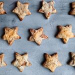 Vue de dessus de délicieux biscuits faits maison en forme d'étoile disposés sur une surface bleue.