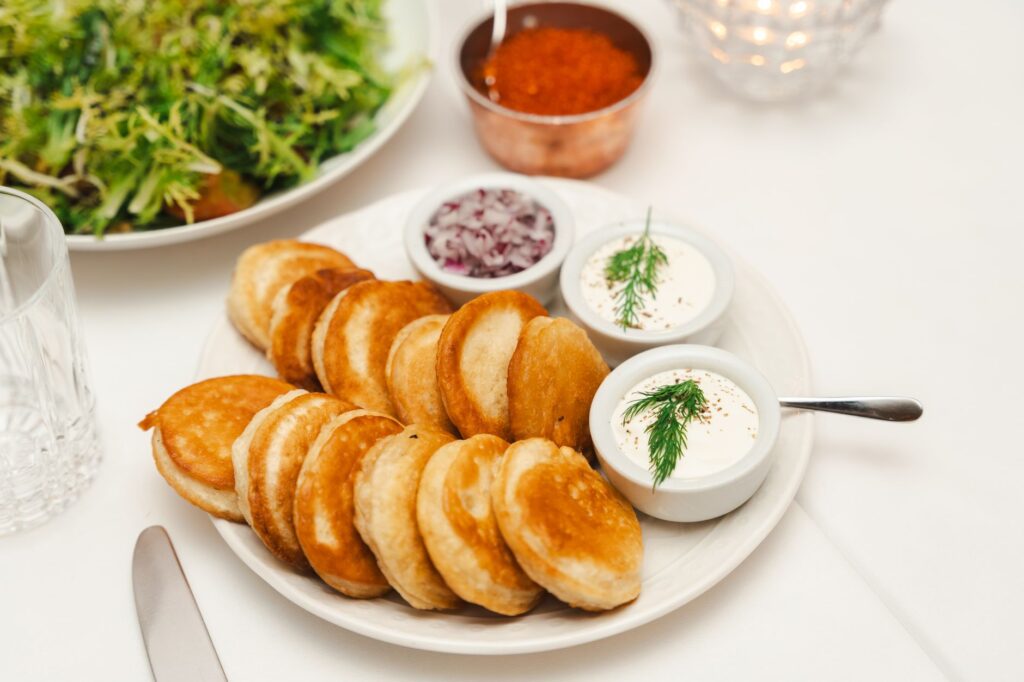 Une assiette de crêpes dorées accompagnées d'une sauce à la crème fraîche et de salade, parfaite pour un repas salé.