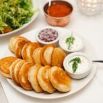 Une assiette de crêpes dorées accompagnées d'une sauce à la crème fraîche et de salade, parfaite pour un repas salé.