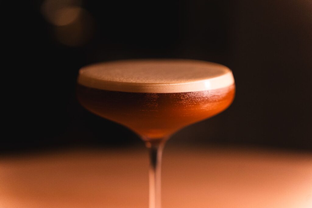 Gros plan sur un verre à cocktail contenant une boisson à plusieurs couches, dans un bar tamisé de Tokyo.