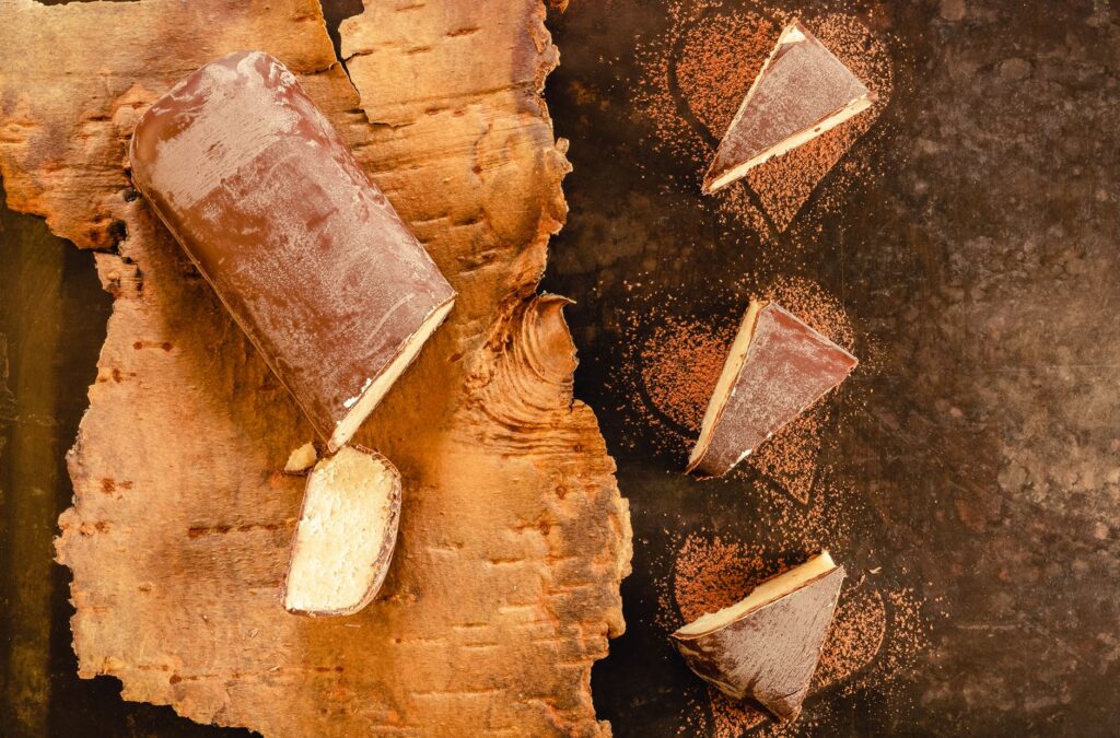 Gros plan d'une bûche de chocolat et de tranches sur un fond de bois et de pierre, photographie culinaire artistique.