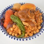 Une assiette colorée de couscous marocain composée d'agneau tendre, de légumes et de pois chiches.