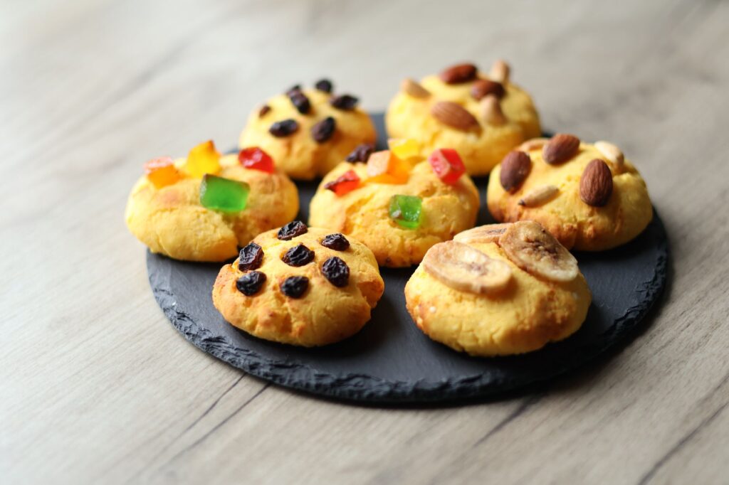De délicieux biscuits maison garnis de noix, de raisins secs et de fruits confits, présentés sur une assiette en ardoise.