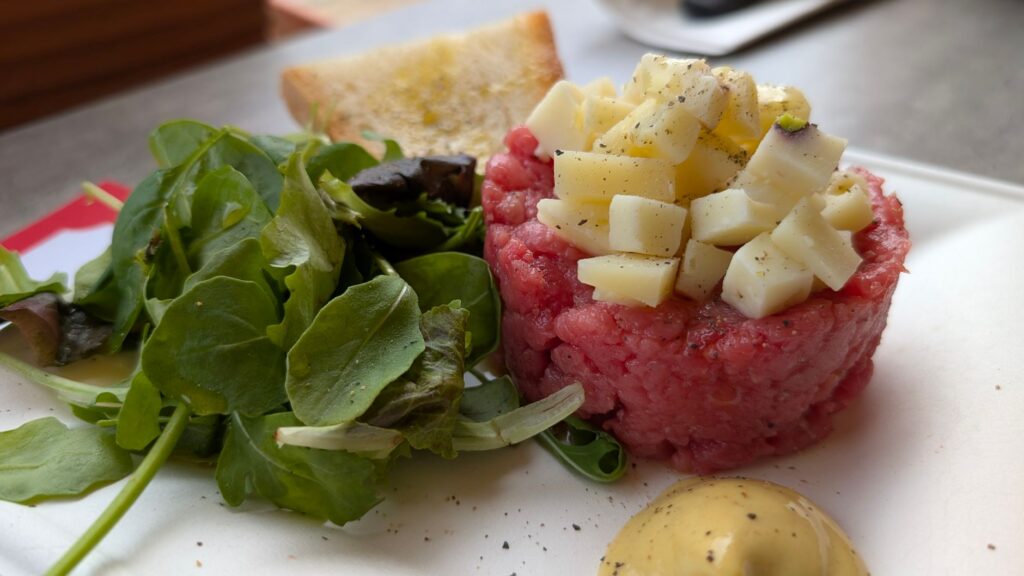 Délicieux tartare de bœuf garni de dés de fromage, servi avec des légumes verts frais et de la moutarde à Greve in Chianti.