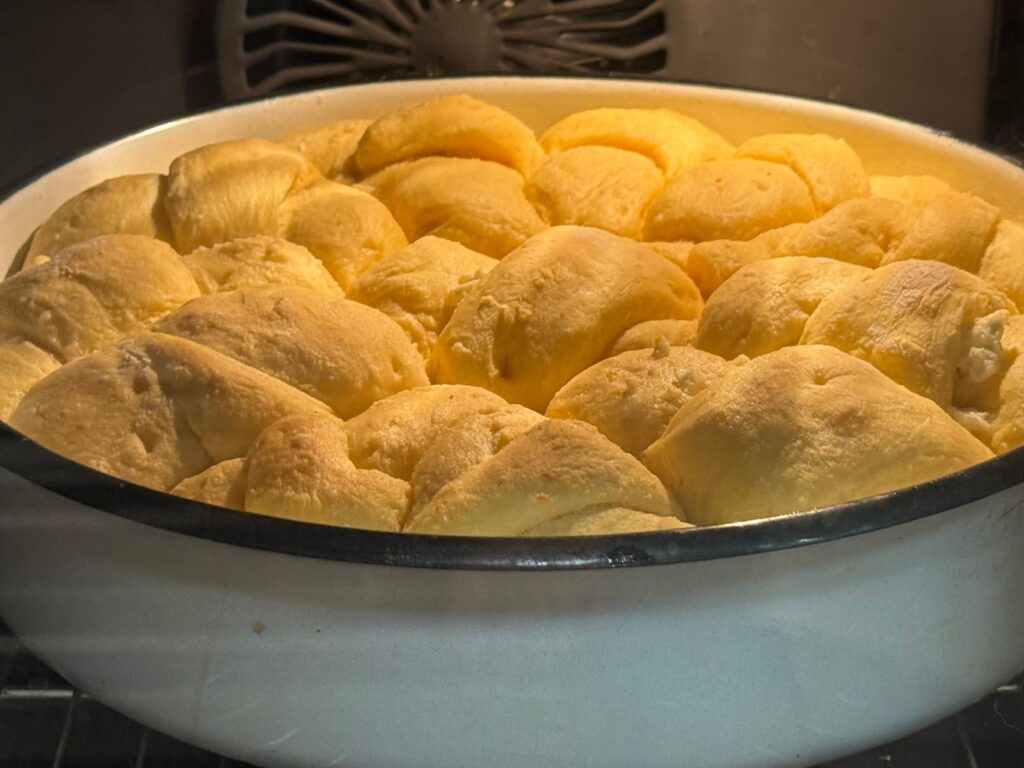 Gros plan sur des petits pains moelleux et dorés qui cuisent au four, créant une ambiance chaleureuse et accueillante.