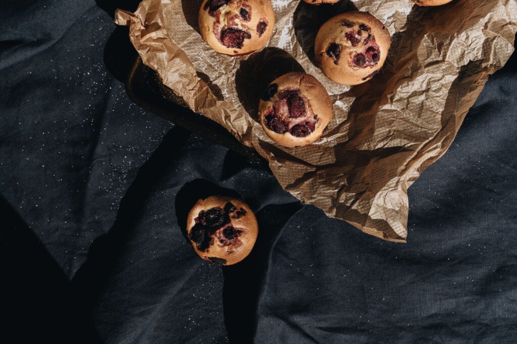 Vue de dessus de muffins aux baies fraîchement cuits sur du papier rustique, parfaits pour la photographie culinaire.