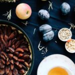 Délicieuse tarte tatin aux prunes faite maison, entourée de fruits frais et de noix.