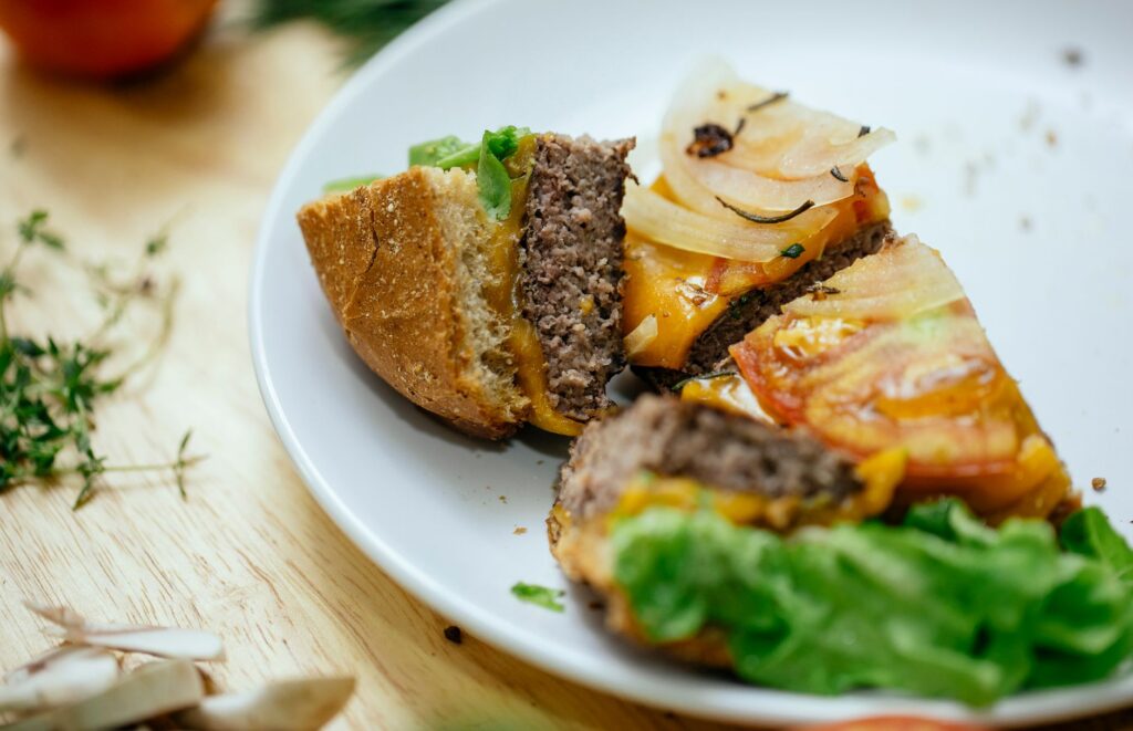 Gros plan sur un burger fait maison avec de la laitue fraîche, des tomates et des oignons sur une assiette blanche.