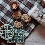 Un décor de table vintage à carreaux avec des biscuits, une lumière de bougie et des éléments décoratifs.
