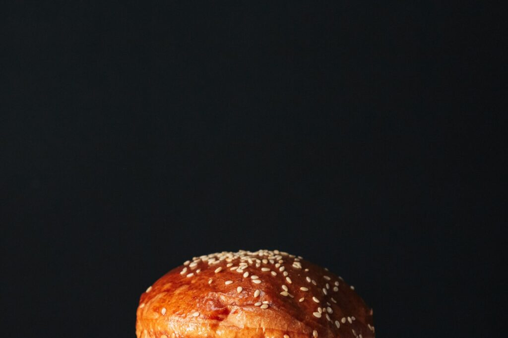 Gros plan sur un délicieux pain à burger aux graines de sésame sur fond sombre, parfait pour la photographie culinaire.