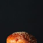 Gros plan sur un délicieux pain à burger aux graines de sésame sur fond sombre, parfait pour la photographie culinaire.