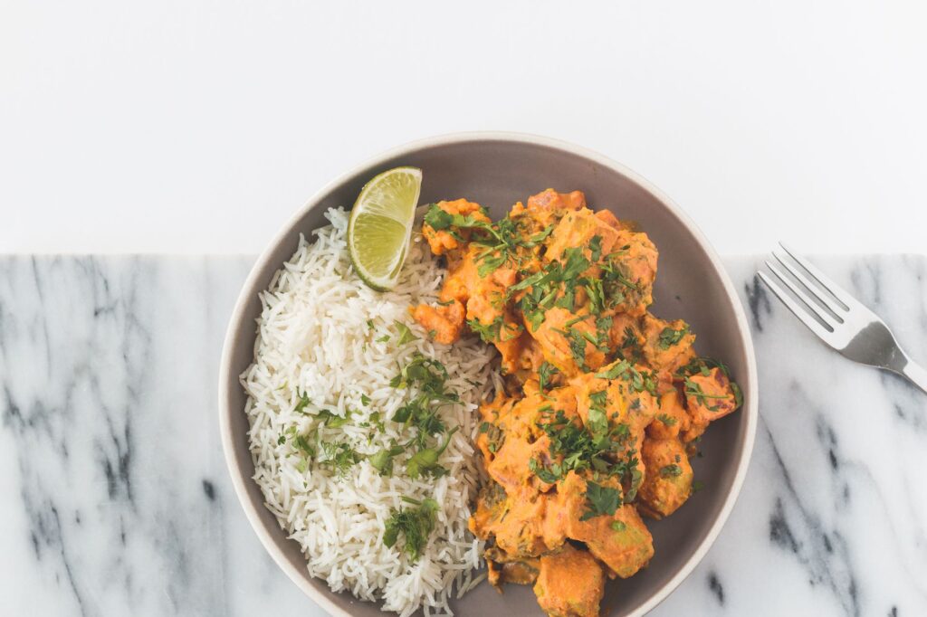 Un curry de poulet vibrant accompagné de riz basmati, garni d'herbes et de citron vert.