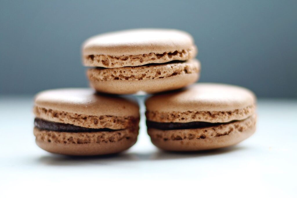 Gros plan de macarons au chocolat empilés mettant en valeur leur texture et leur garniture.