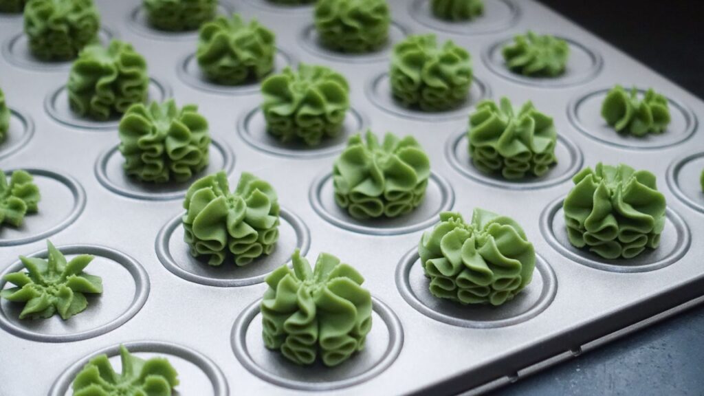 Délicieux biscuits verts en forme de fleur disposés sur une plaque de cuisson.