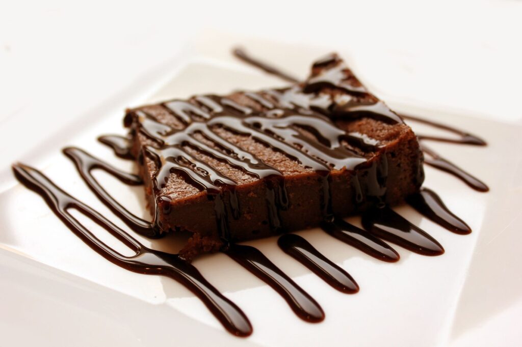 Brownie au chocolat riche arrosé de sirop sur une assiette blanche propre, parfait pour les amateurs de desserts.