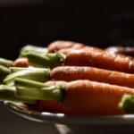 Gros plan de carottes biologiques fraîches avec des feuilles vertes dans un éclairage dramatique, mettant en avant la texture.
