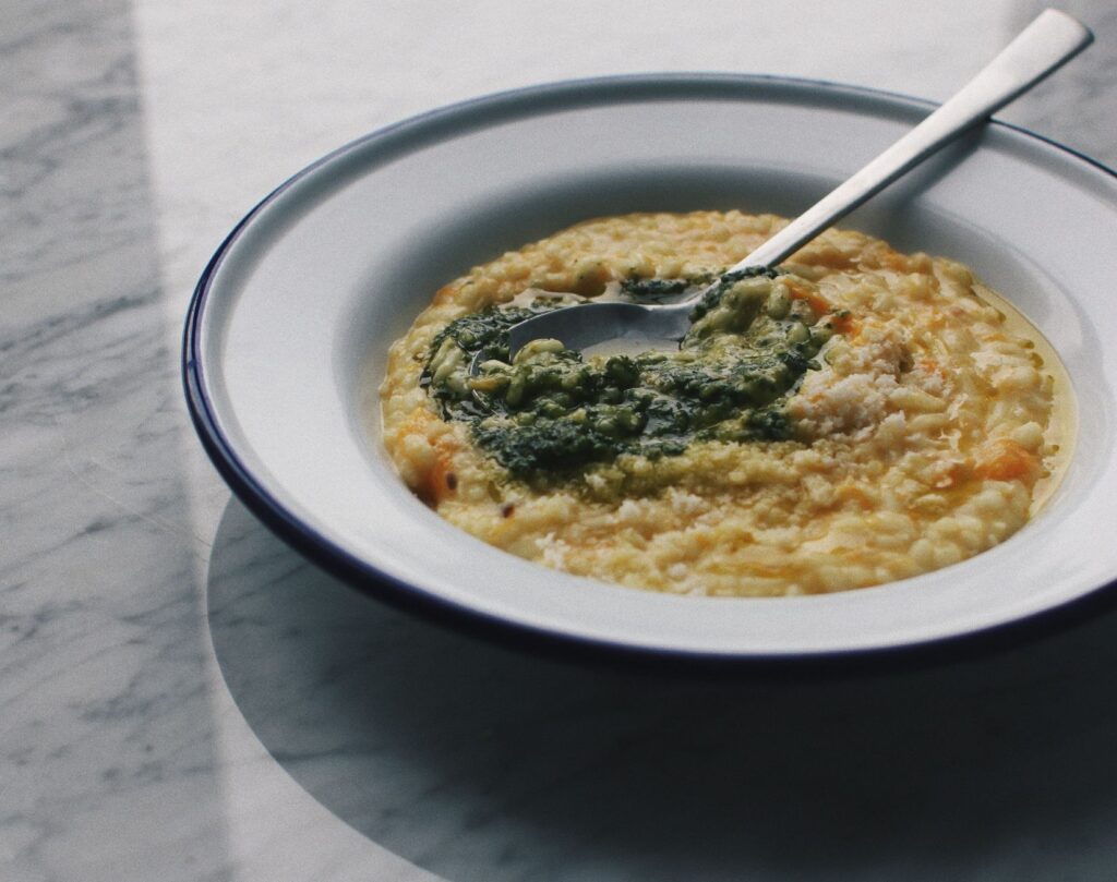Délicieux bol de risotto crémeux surmonté de sauce pesto, idéal pour la photographie culinaire.