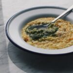 Délicieux bol de risotto crémeux surmonté de sauce pesto, idéal pour la photographie culinaire.