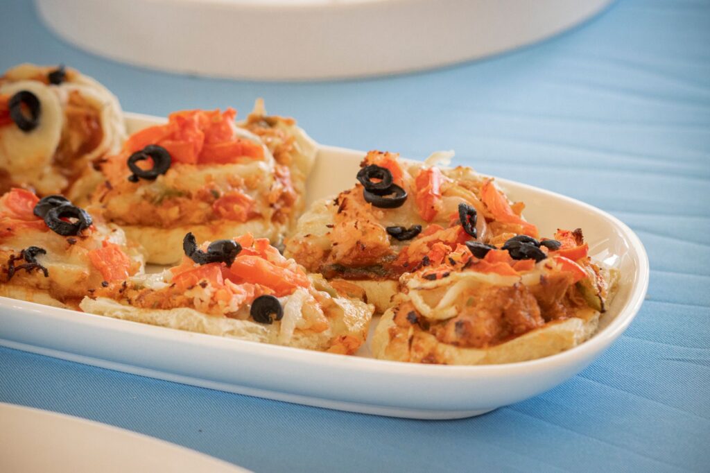 Délicieuses mini pizzas garnies d'olives noires et de tomates sur une assiette blanche.