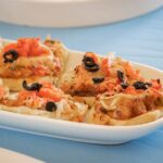 Délicieuses mini pizzas garnies d'olives noires et de tomates sur une assiette blanche.