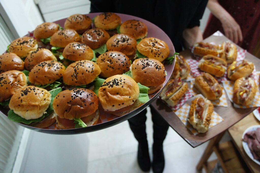 Gros plan de plateaux avec des mini-burgers et des hot dogs variés, parfaits pour les fêtes.