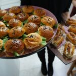 Gros plan de plateaux avec des mini-burgers et des hot dogs variés, parfaits pour les fêtes.