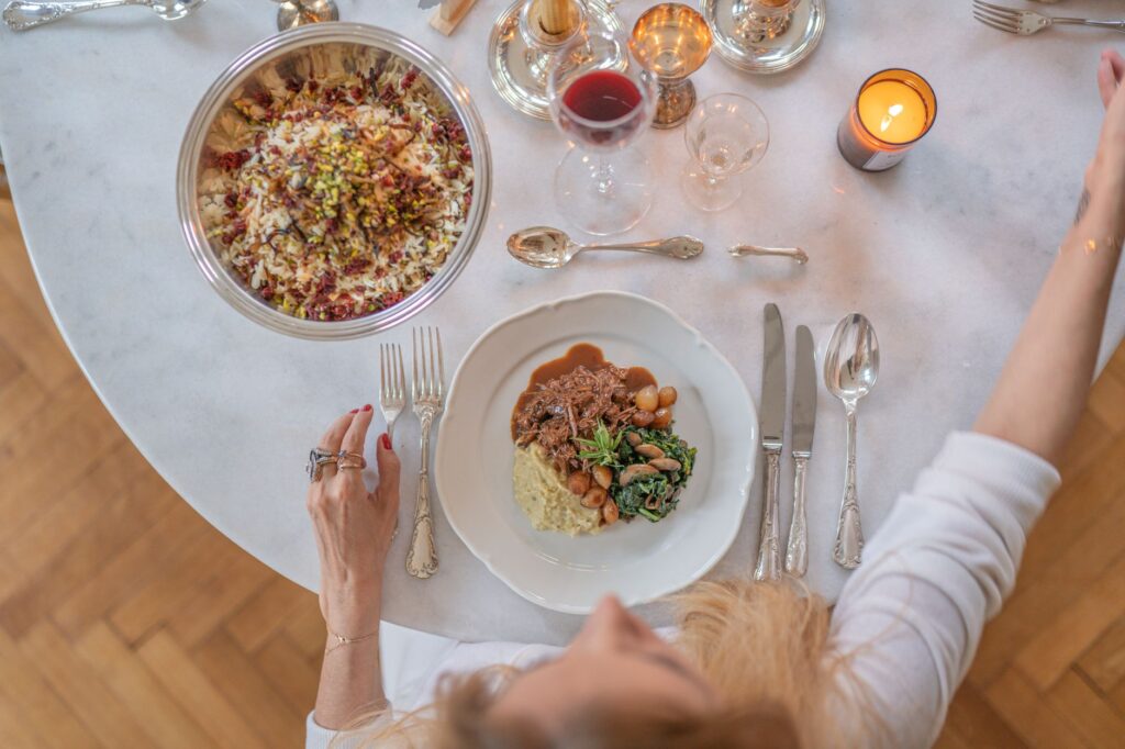 Vue de dessus d'une table raffinée avec un plat principal, du vin rouge et une bougie allumée, mettant en avant une occasion spéciale.