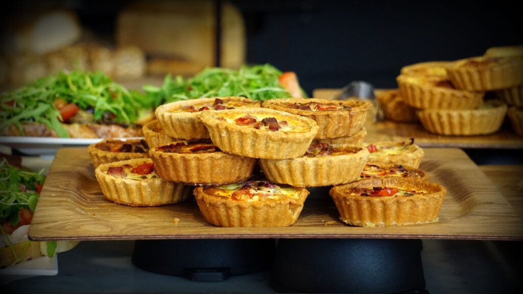 Une présentation tentante de quiches maison garnies d'ingrédients frais sur un plateau en bois.