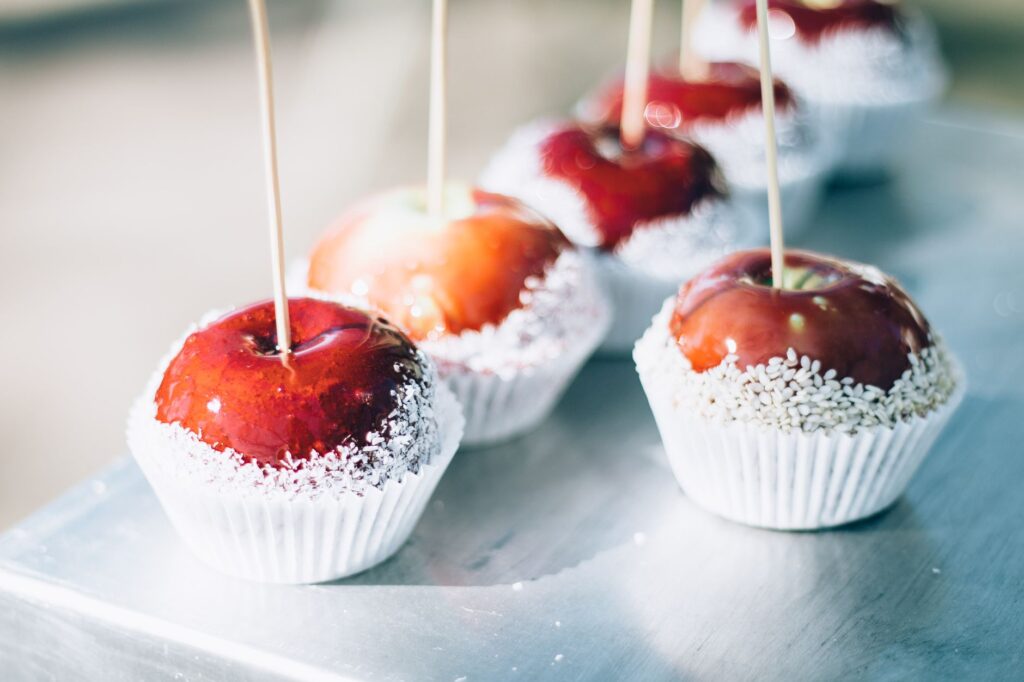 Gros plan sur des pommes au caramel rouge avec un enrobage de sucre sur des bâtons. Parfait pour des thèmes de sucreries et confiseries.