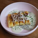 Une présentation alléchante de crêpes garnies d'une riche sauce aux champignons et d'herbes servies dans une assiette rose.
