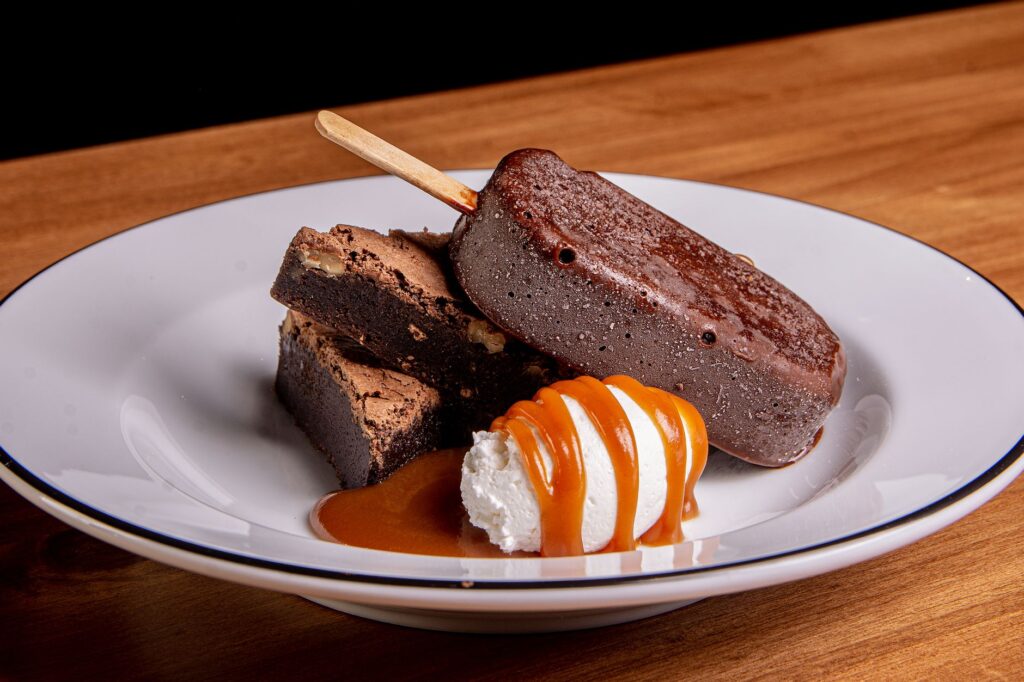 Délicieux brownie au chocolat avec glace et sauce caramel sur une assiette.