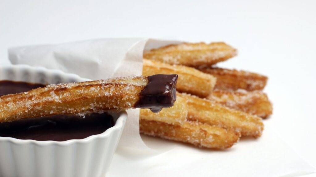 Délicieux churros enrobés de sucre, trempés dans une sauce au chocolat riche, parfaits pour les amateurs de desserts.