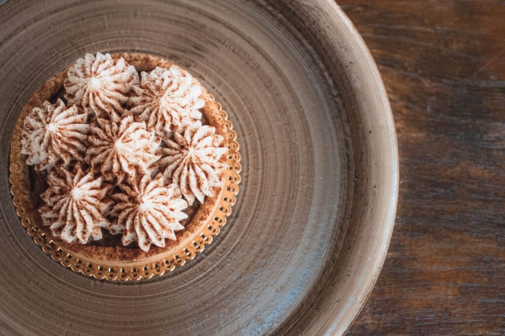 Un gros plan d'une pâtisserie en crème joliment décorée sur une assiette en bois, parfait pour la photographie culinaire.