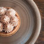 Un gros plan d'une pâtisserie en crème joliment décorée sur une assiette en bois, parfait pour la photographie culinaire.