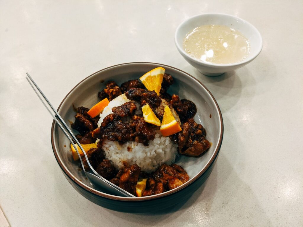 Savourez un repas asiatique gourmet avec de la viande, du riz et des tranches d'orange, servi avec une soupe.