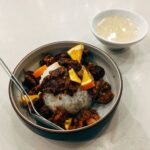 Savourez un repas asiatique gourmet avec de la viande, du riz et des tranches d'orange, servi avec une soupe.