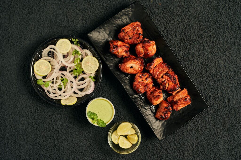Plan large de morceaux juteux de poulet tandoori avec salade d'oignons et chutney vert, parfait pour les amateurs de cuisine indienne.