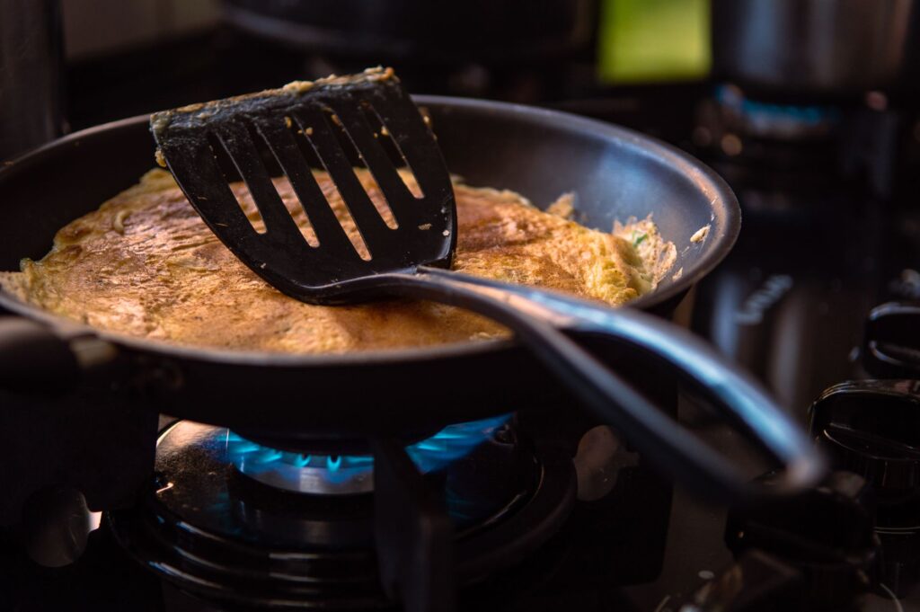 Une omelette parfaitement cuite dans une poêle avec une spatule sur une cuisinière.