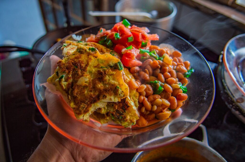 Délicieuse omelette servie avec des haricots et une salsa fraîche dans une assiette transparente.