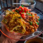 Délicieuse omelette servie avec des haricots et une salsa fraîche dans une assiette transparente.