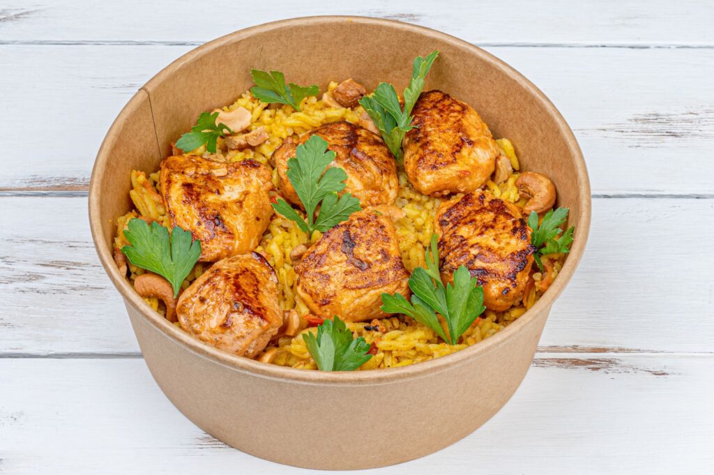 Délicieux poulet frit servi sur du riz assaisonné avec du persil dans un bol à emporter.