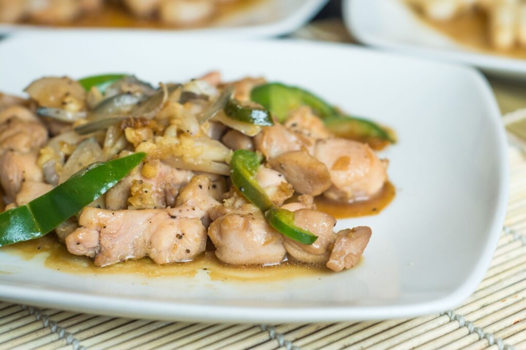 Gros plan d'un délicieux sauté de poulet avec des légumes servi sur une assiette blanche.