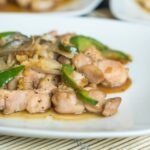 Gros plan d'un délicieux sauté de poulet avec des légumes servi sur une assiette blanche.