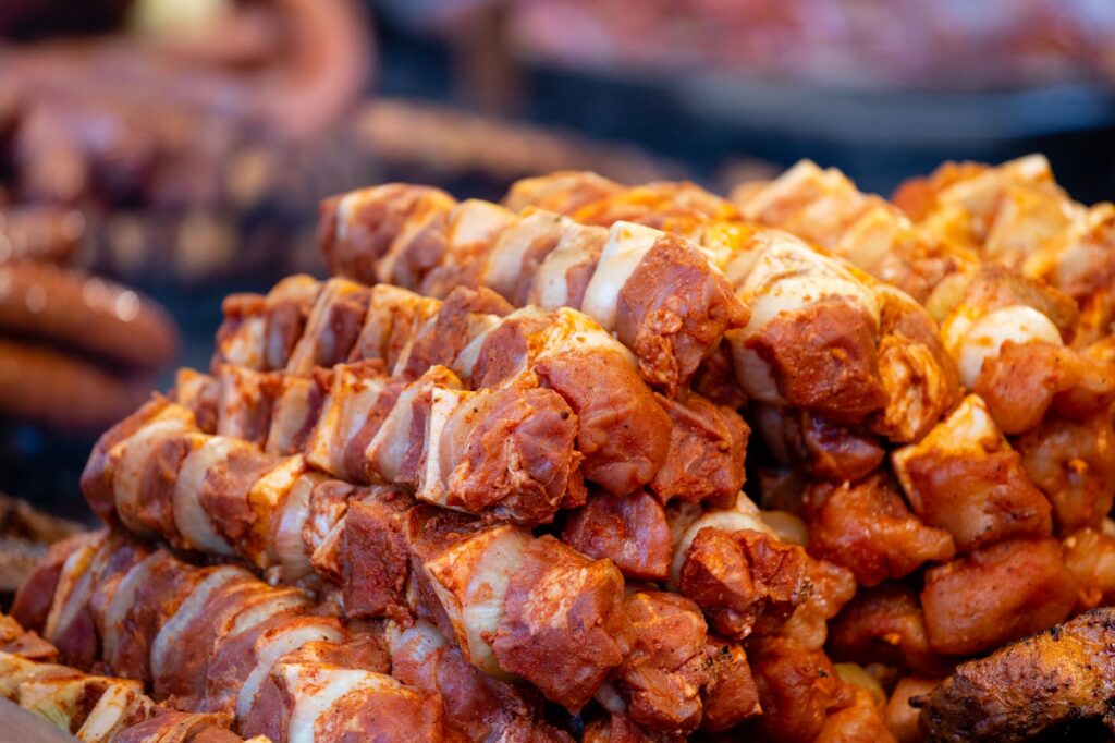 Juteuses brochettes de porc mariné empilées sur un barbecue, prêtes à être grillées.