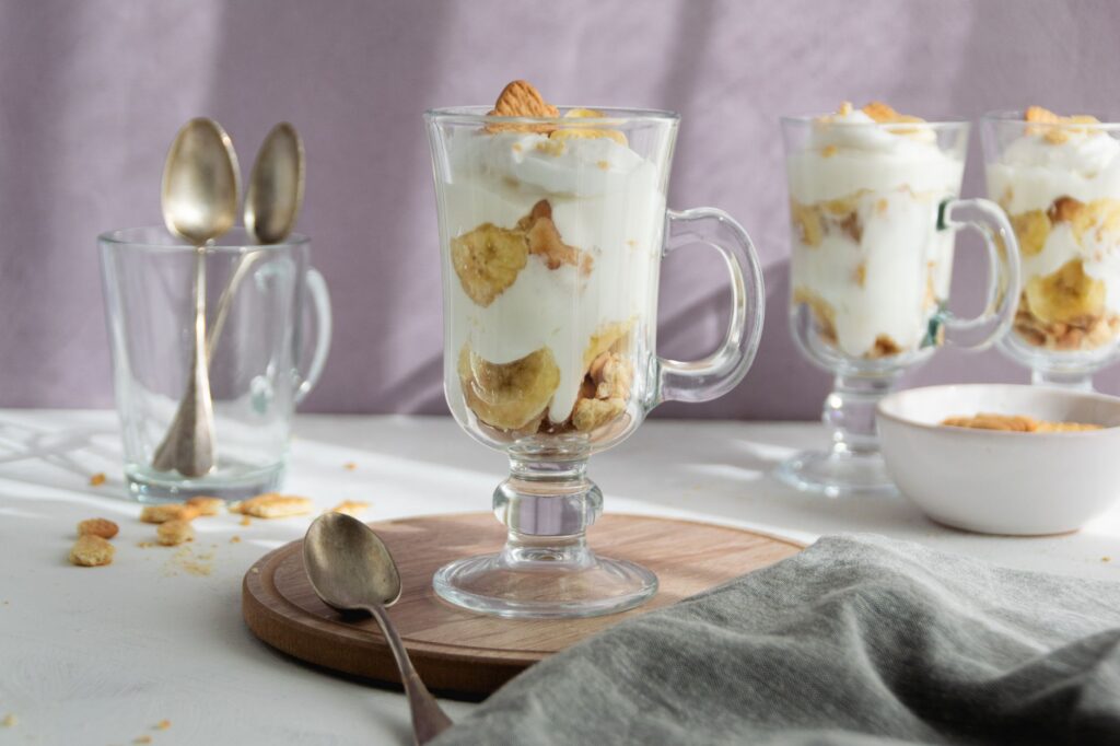 Délicieuses couches de parfait à la banane avec du yaourt crémeux dans une tasse en verre, parfait pour une douce friandise.