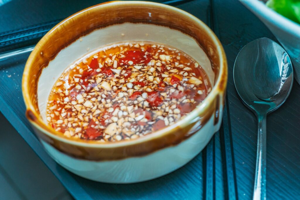 Gros plan sur une sauce piquante avec de l'ail haché et des piments dans un bol rustique sur une table.
