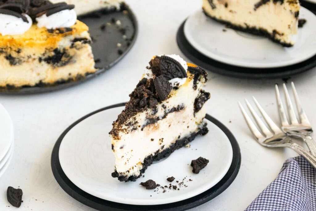 Gros plan d'un cheesecake Oreo tranché sur une assiette en céramique, parfait pour les amateurs de dessert.