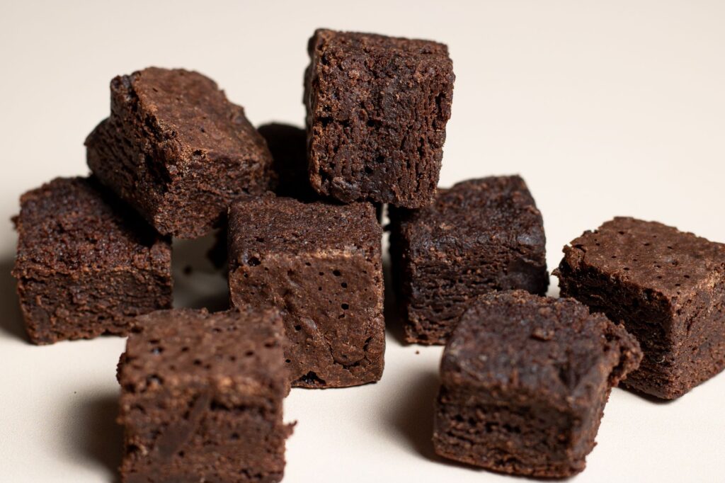 Gros plan de cubes de brownie au chocolat riche sur un fond neutre, parfait pour les amateurs de desserts.
