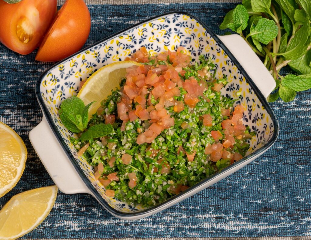 Salade colorée de taboulé avec des tomates, du citron et de la menthe servie dans un bol décoratif pour un repas délicieux.